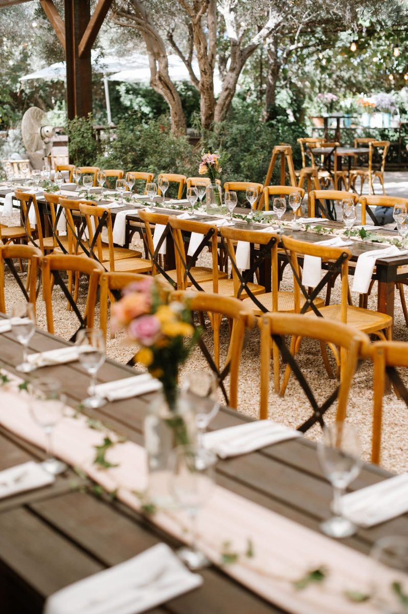 A long table set for a wedding, with bud vases and ivy